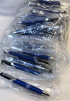 Multiple black ink pens with blue matte barrels and silver clips individually wrapped in clear plastic bags.