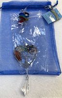 Full view of suncatcher inside plastic bag with blue organza pouch and product tag