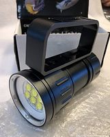 Close-up of black LED diving flashlight with six LED bulbs visible behind lens and attached rectangular handle mount.