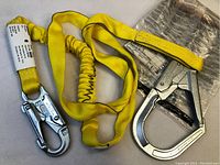 Full view of yellow 7ft lanyard with two metal locking snap hooks and attached packaging.