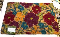 Front view of the rectangular coir doormat showing vibrant multicolor floral pattern with colors including red, purple, orange, green, and blue on natural brown coir fibers.