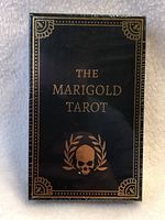 Front of the sealed Marigold Tarot card deck box showing title and decorative gold skull design.
