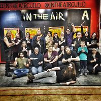 Group of participants posing with throwing knives in front of 'In The Air' wall sign