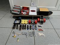 Top-down view of all items laid out: adult skateboard, remote control skateboard, mini finger skateboards, ramps, wheels, tools, and stickers.
