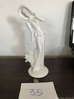 Full view of white porcelain figurine showing entire figure standing with decorative floral base.