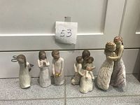 Six Willow Tree figurines arranged on floor with tag number 53 behind them.