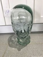 Front view of the clear glass head sculpture, showing facial features.