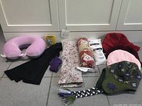 Full lot showing various handmade hats, neck pillow, socks, and other warmers lined up on floor.