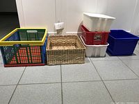 Photo showing various storage bins and baskets including plastic bins in multiple colors, collapsible straw basket, and woven baskets.