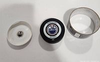 Three-piece image showing the hockey puck with Edmonton Oilers logo, and two-piece transparent display case top and bottom.