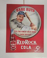 Front view of red tin sign with Babe Ruth holding a bat and Red Rock Cola bottle image