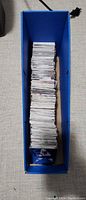 Vertical view of a blue storage box filled with a large quantity of hockey cards stacked upright.
