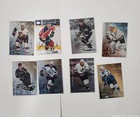 Front view of eight autographed NHL hockey cards showing players in action and team uniforms with visible signatures.