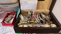 Wooden jewelry box with assorted bangles, beads, earrings, rings and envelope labeled ‘Cuba Coins’