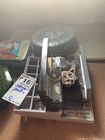 Photo showing jewelry lot with a gray jewelry organizer containing rings and earrings, a plastic box with faux pearl necklaces, and tins.