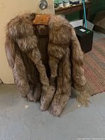 Full view of large fit Top Furs fox fur jacket with attached fur scarf hanging on wooden hanger. Shows dense natural fox fur in light to medium brown shades.