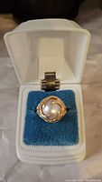 Ring presented in white jewelry box with blue cushion