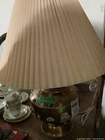 Full lamp showing brass base with natural stone design and pleated fabric shade.