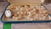 Double-strand mother of pearl bead necklace with detailed cameo clasp placed in box