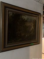 Frontal view of framed oil painting hanging on a white textured wall