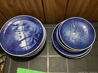 Fifteen Royal Copenhagen plates in blue and white with nature and animal motifs including palm trees, birds, squirrels, horses, and foals with detailed border decorations, dated 1972 and 1973.