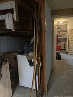 Side view showing two vintage wooden skis leaning against the wall, one with wood showing and bindings attached.