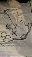 Two chains, cross pendant and pair of clip-on earrings laid on white background