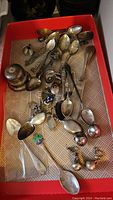 Overview of red tray containing ring box parts, teaspoons and earrings