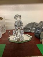 Clear Swarovski crystal panther figurine sitting on octagonal mirror base. Side and top views.