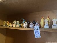 Shelf showing several vintage ceramic salt and pepper shaker sets including chicks, hens, corn ears, and a ceramic basket