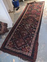 Full length of the Persian wool runner laid on the floor showing the complete geometric diamond motif design and fringing on the edges.