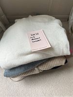 Stack of four cashmere sweaters as viewed from above showing the folded clothes with a sticker indicating '100% cashmere sweaters'.