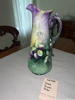Front view of the porcelain pitcher showing hand-painted grape design and color gradient.