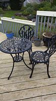 Full view of black metal bistro table with two matching chairs on a deck
