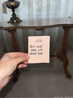 Full view of the table showing carved legs and stretcher base beneath a smooth burr wood top with scalloped edges.