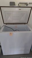 Open top view showing the inside of the chest freezer with a black power cord and white wire basket.
