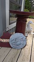 Image showing the red bird bath pedestal, decorative relief plaque, and red welcome sign on the porch