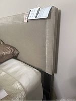Full view of beige upholstered king headboard attached to frame