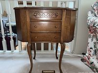 Full front view of the wooden sewing cabinet showing carved details and fold-out side units.