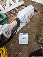 Close-up of Stihl FSE 60 label and blower portion of weed eater tool alongside note showing lot details.