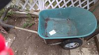 Full view of the green wheelbarrow showing the tub, wheel, and handles.