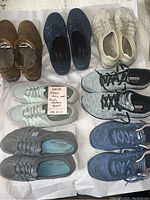 Lot of 8 women's shoes displayed on white background, showing various styles and brands including Skechers and Ugg ankle boots.