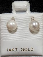 Front view of 14K gold earrings with white freshwater pearls and small diamonds on a white display card stamped "14KT. GOLD".