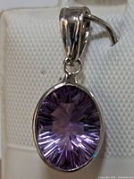 Close-up photo of the oval cut amethyst pendant in 14K gold, showing the side angle and gemstone facets.