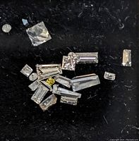 Close up photo of multiple loose baguette cut diamonds and other small stones on black background showing clarity and shape details.