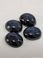 Four polished dark blue star sapphires showing their cabochon shape and star effect.