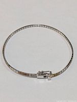 Full view of the silver bangle bracelet showing the circular form and clasp