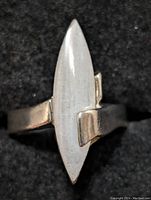 Close-up front view of a marquise-shaped mother of pearl ring set in sterling silver on a black background.