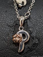 Close-up front view of 'P' initial pendant with rose gold-tone flower and diamond accent on black background
