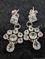 Pair of sterling silver drop earrings with multiple blue topaz stones on a black background.